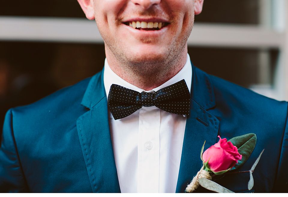 Der Bräutigam trägt eine Ansteckblume und lächelt in die Kamera.