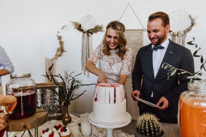 Eine Braut und ein Bräutigam schneiden bei einer Hochzeitsfeier eine Torte an.