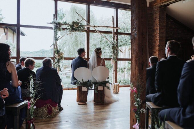Eine Hochzeitszeremonie in einer Scheune mit großen Fenstern.