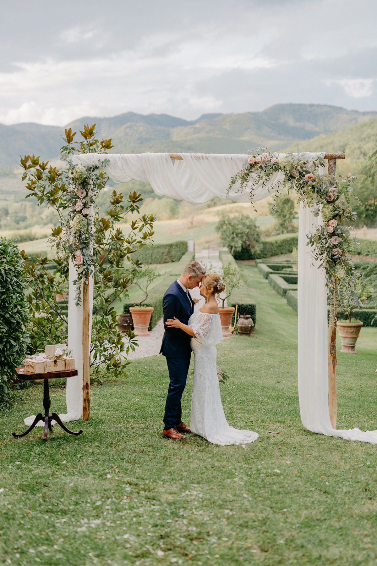 Eine Braut und ein Bräutigam küssen sich unter einem Torbogen in der Toskana.