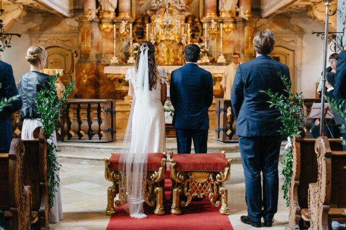 Eine Hochzeitszeremonie in einer Kirche mit einem Brautpaar, das auf den Kirchenbänken sitzt.