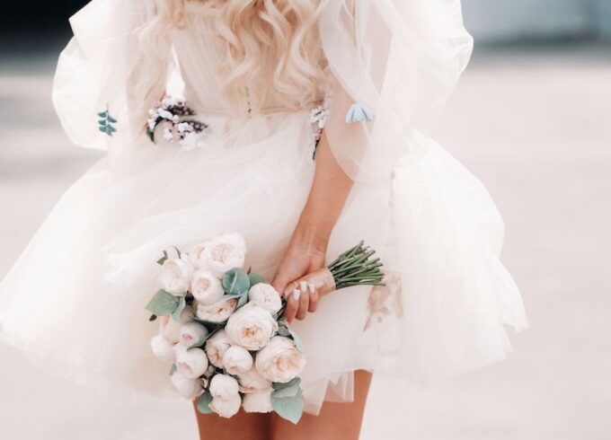 Eine Frau in einem weißen Kleid hält einen Strauß Rosen.