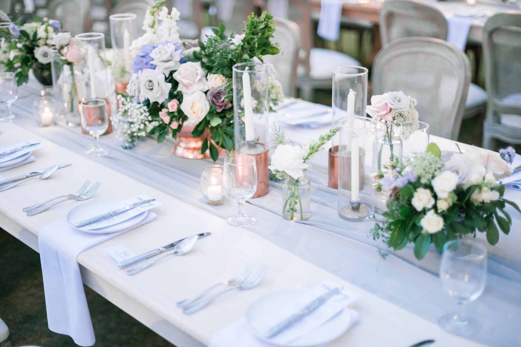 Ein langer Tisch, gedeckt mit Blumen und Besteck.