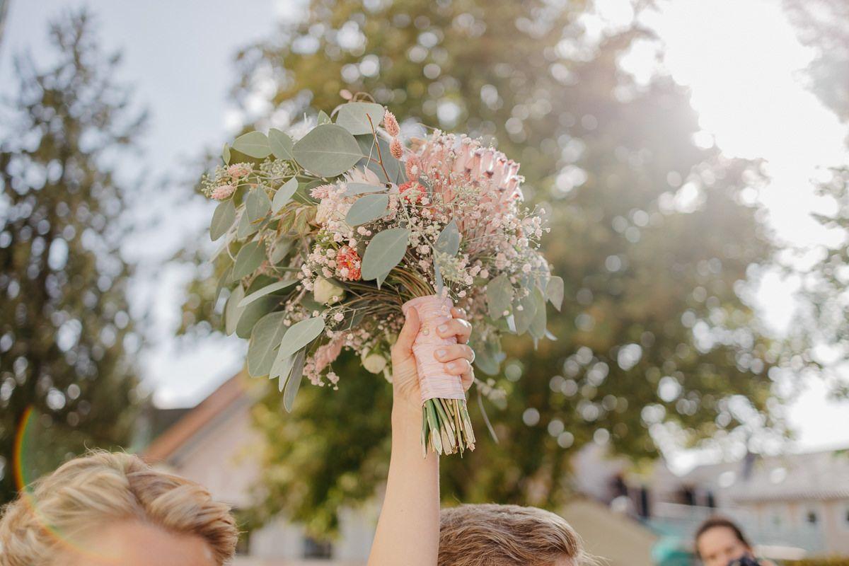 Zwei Brautjungfern halten Blumensträuße in die Luft.
