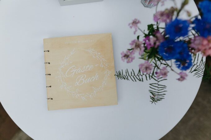 Ein Hochzeitsgästebuch auf einem Tisch neben Blumen.