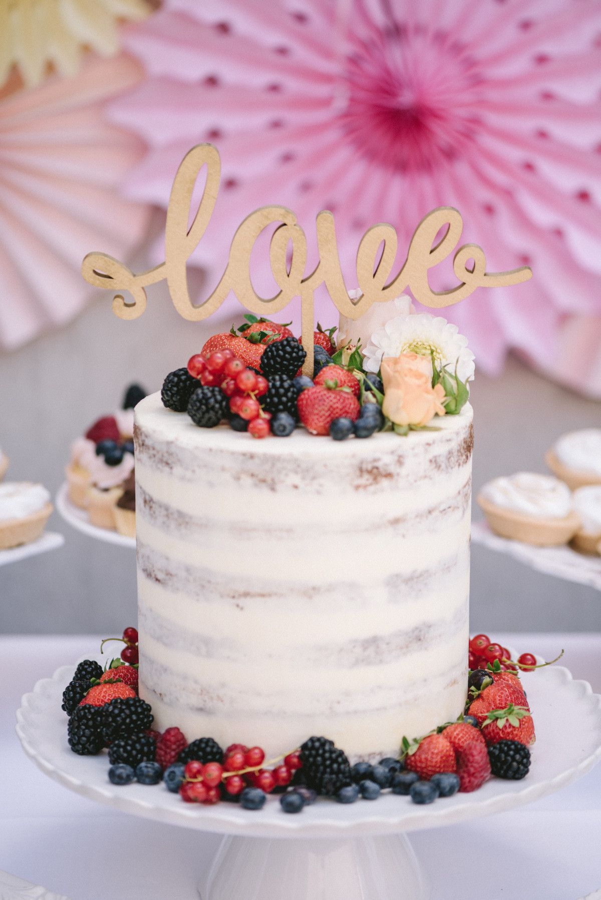 Eine Torte mit Beeren und einem Tortenaufsatz mit dem Wort Liebe.