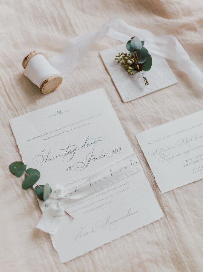 Eine weiße Hochzeitseinladung mit Eukalyptus und Eukalyptusblättern.