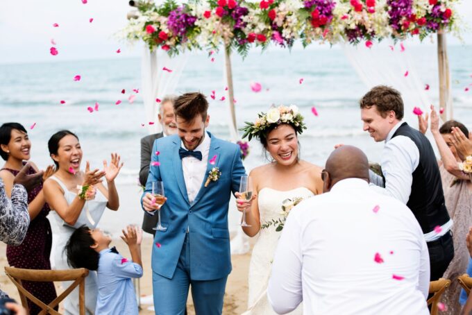 Eine Hochzeitszeremonie am Strand, bei der Braut und Bräutigam mit Konfetti beworfen werden.