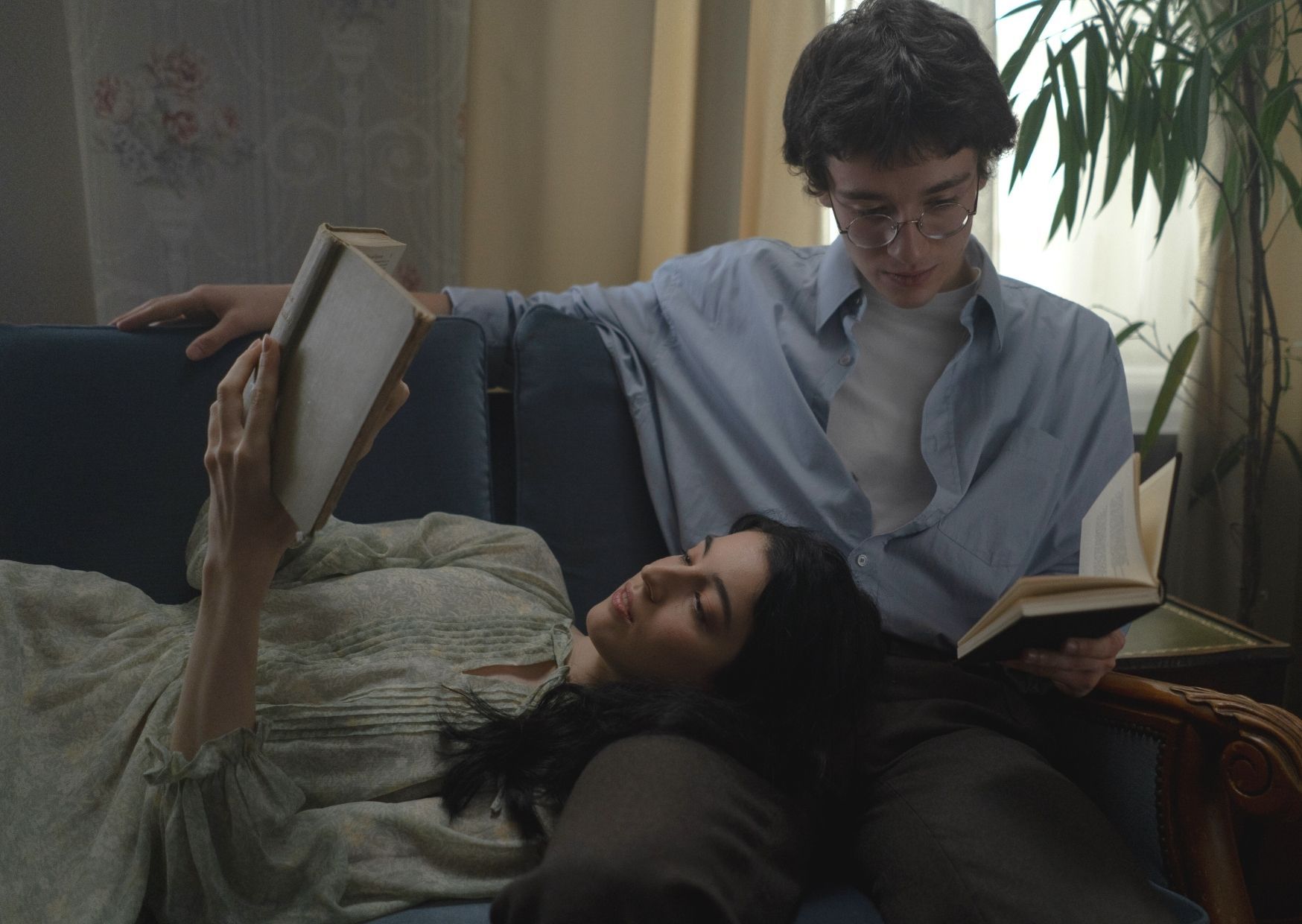 Paar sitzt bzw. liegt auf dem Sofa und hält jeweils ein Buch in der Hand 