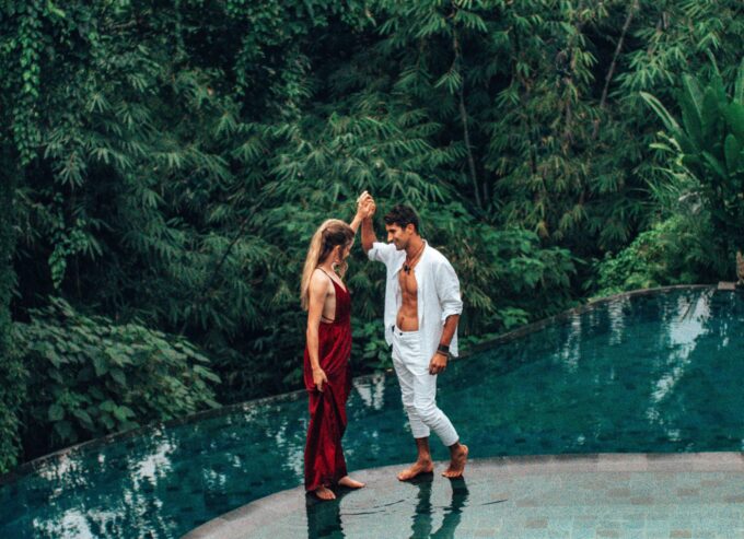 Ein Mann und eine Frau stehen neben einem Pool im Dschungel.