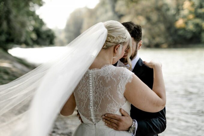 Eine Braut und ein Bräutigam umarmen sich in der Nähe eines Flusses.