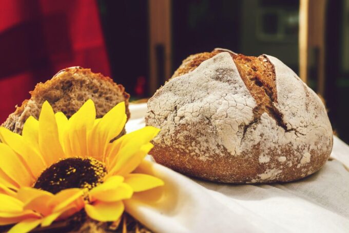 Ein Laib Brot liegt auf einem Tisch neben einer Sonnenblume.