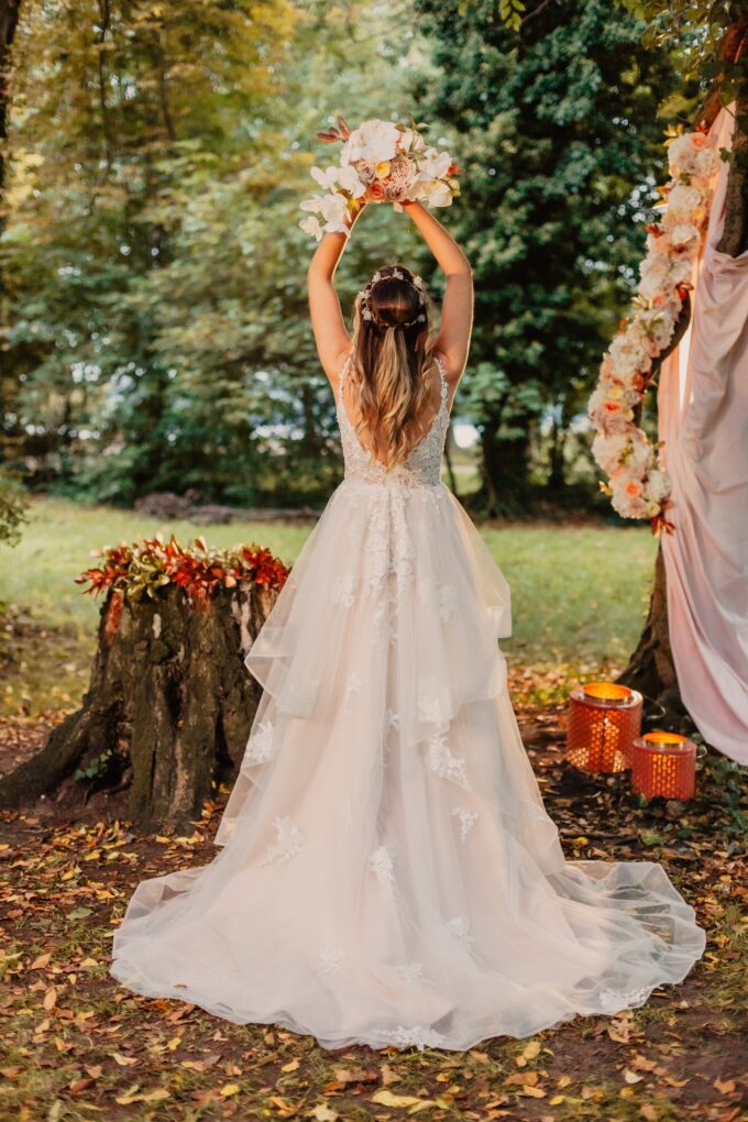 Eine Braut posiert vor einem Baum im Wald.