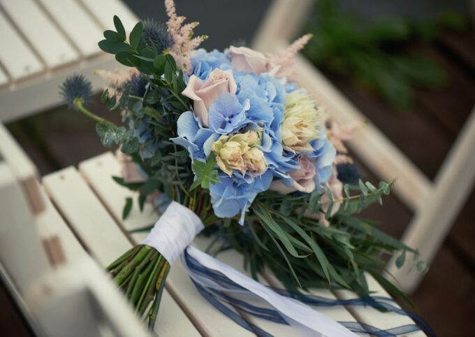 Auf einem weißen Stuhl sitzt ein Strauß blau-weißer Blumen.