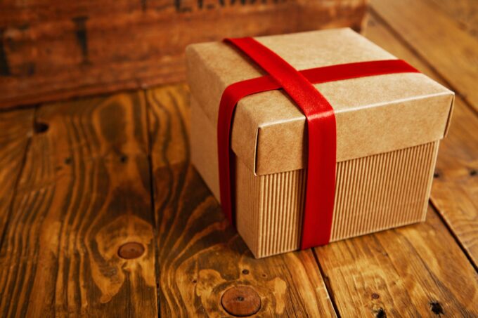 Eine Geschenkbox mit roter Schleife auf einem Holztisch.