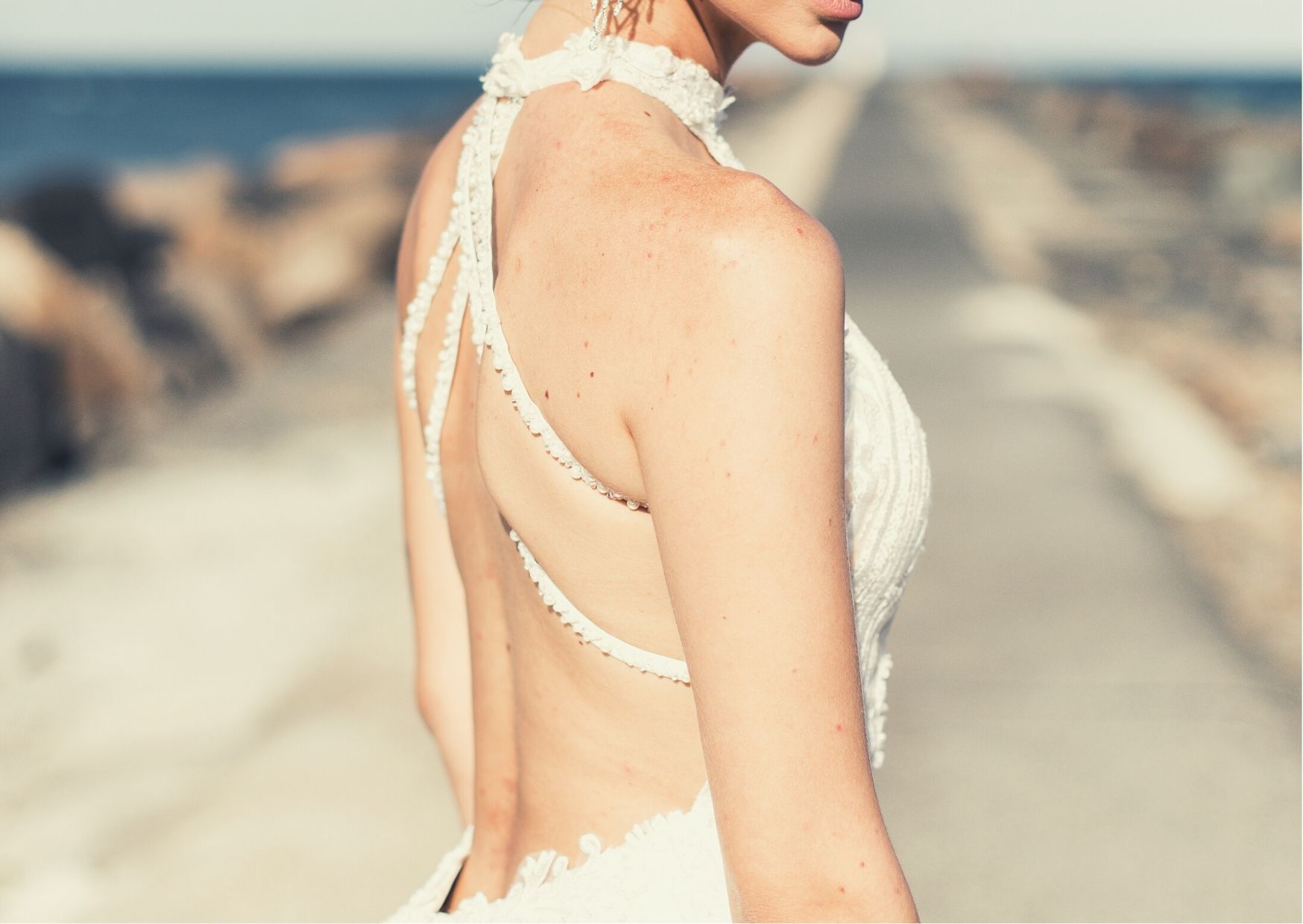 Braut im Neckholder Kleid mit Perlen am Rücken von Hinten zu sehen
