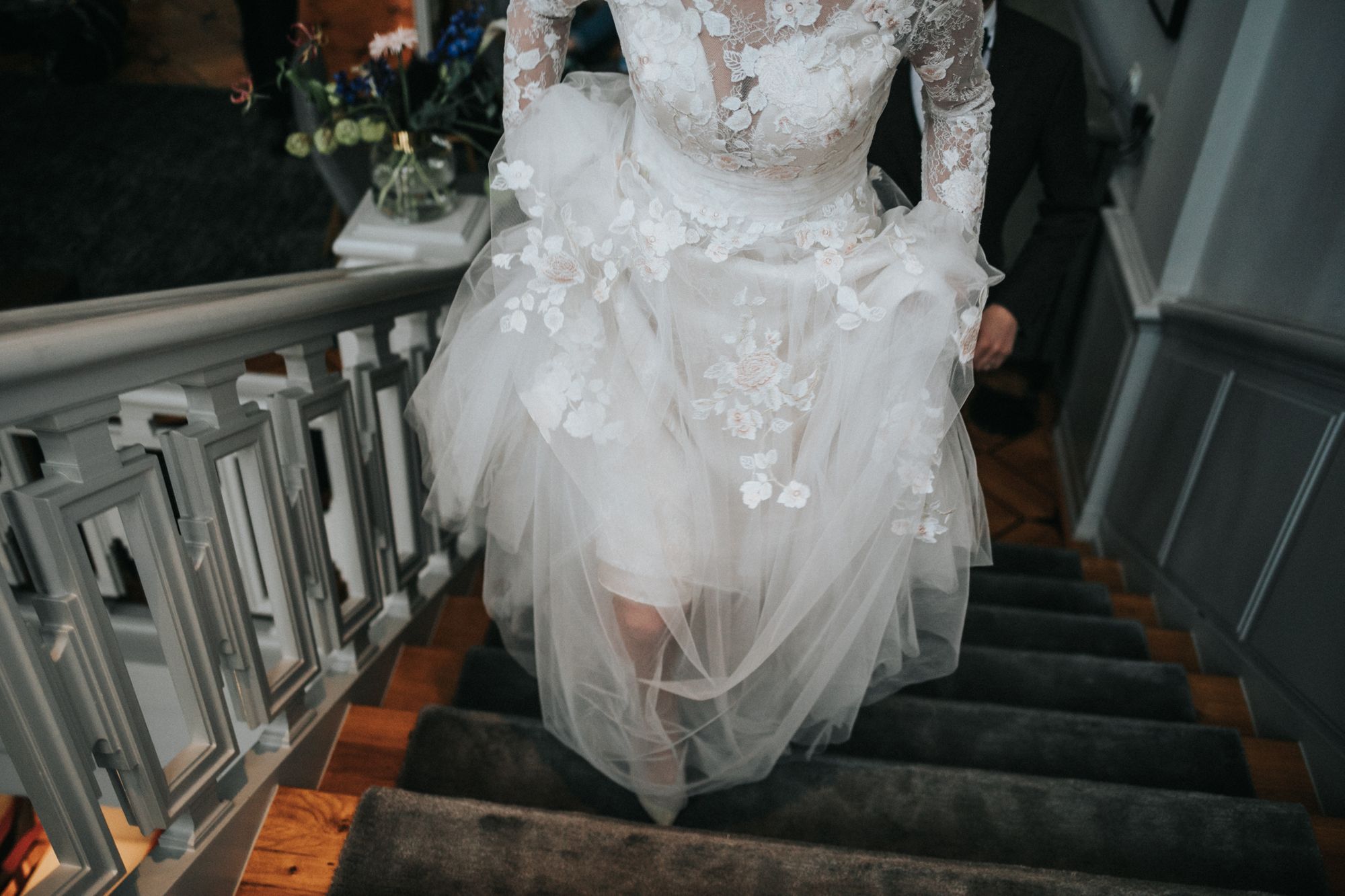 Eine Braut geht in ihrem Hochzeitskleid die Treppe hinunter.