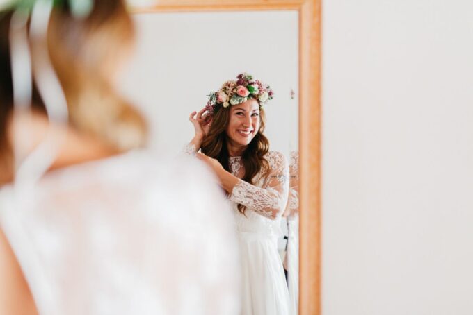 Eine Braut macht sich vor einem Spiegel fertig.