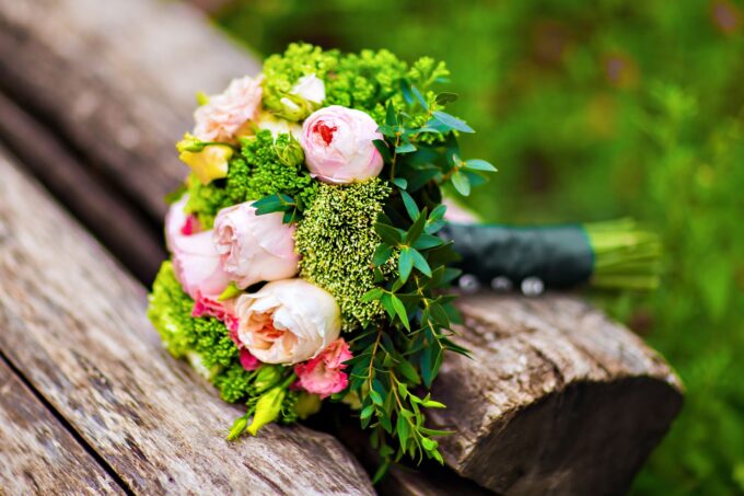 Ein Blumenstrauß sitzt auf einer Holzbank.