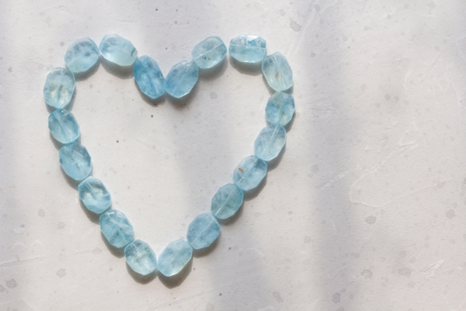 Ein Herz aus blauen Topassteinen auf einer weißen Oberfläche.