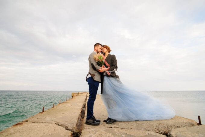 Eine Braut und ein Bräutigam stehen auf einem Pier am Meer.
