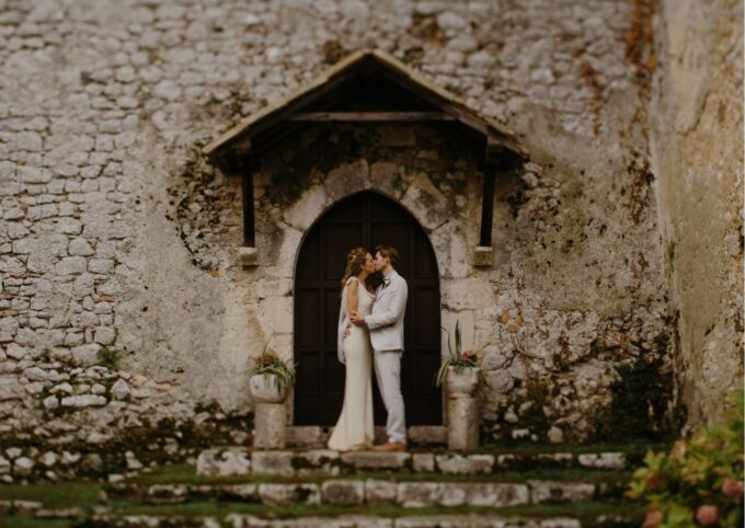 Eine Braut und ein Bräutigam stehen vor einem alten Steingebäude.