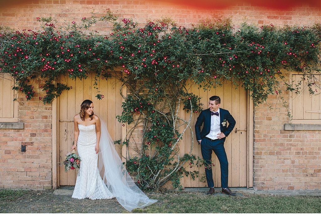 Eine Braut und ein Bräutigam stehen vor einem Backsteingebäude.