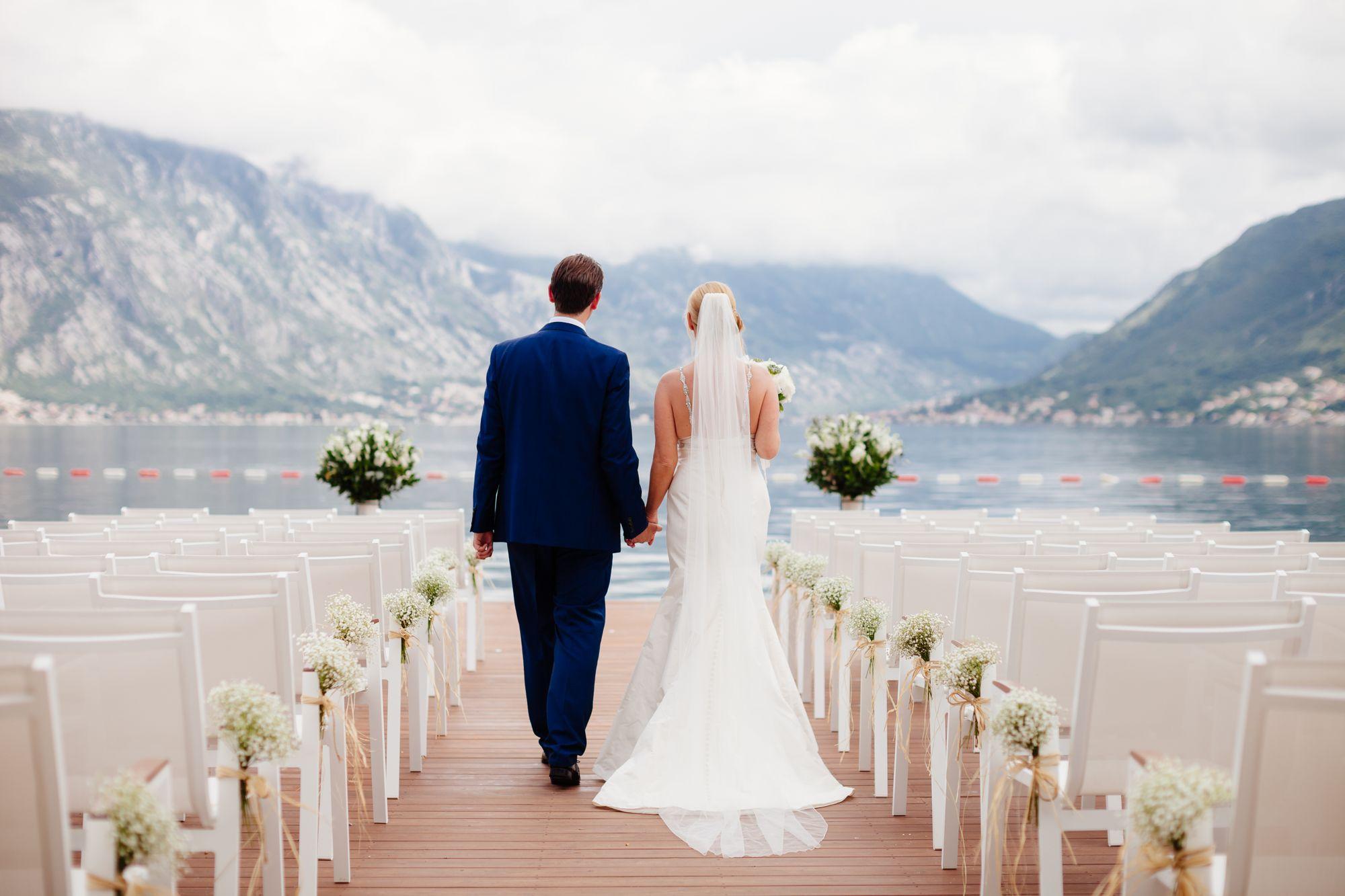 Eine Braut und ein Bräutigam gehen bei einer Hochzeit am See den Altar entlang.