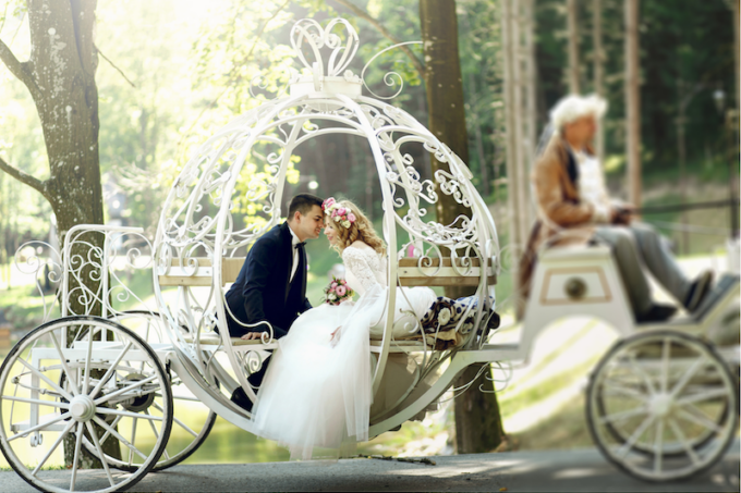Ein Brautpaar sitzt in einer weißen Kutsche.
