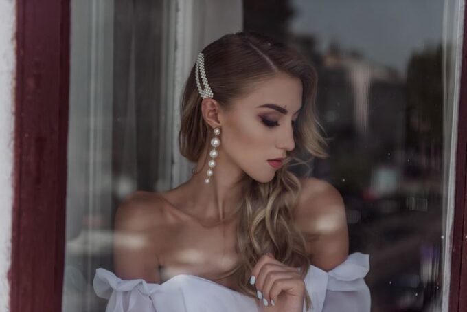 Eine schöne Frau in einem weißen Kleid schaut aus einem Fenster.
