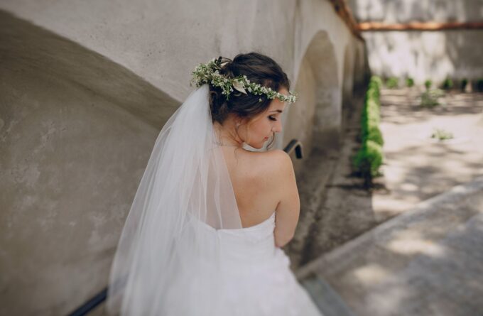 Eine Braut in einem Hochzeitskleid steht auf einer Steinmauer.