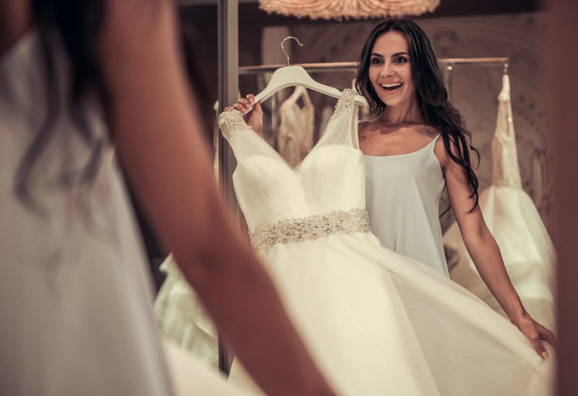 Eine Braut betrachtet ihr Hochzeitskleid im Spiegel.