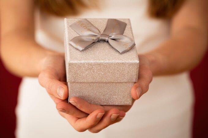 Eine Frau hält eine silberne Geschenkbox mit einer Schleife.
