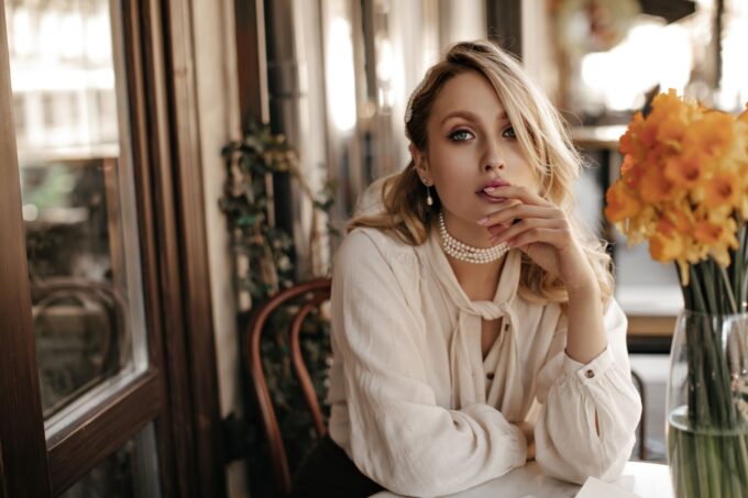Eine blonde Frau sitzt an einem Tisch mit Blumen.