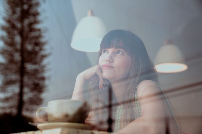 Eine Frau sitzt an einem Tisch und schaut aus dem Fenster.