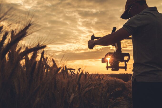 Ein Mann hält bei Sonnenuntergang eine Drohne in einem Weizenfeld.