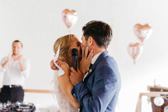 Eine Braut und ein Bräutigam küssen sich bei ihrer Hochzeitsfeier.
