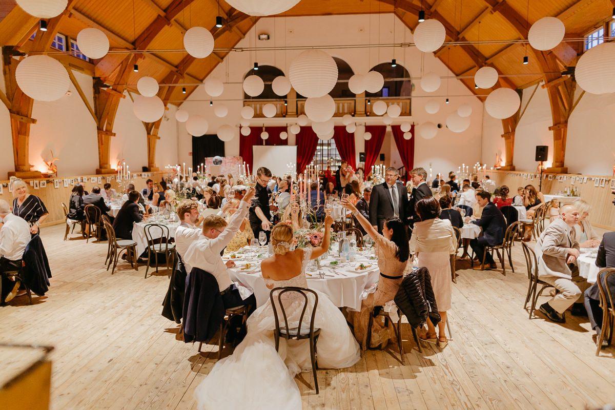 Ein Hochzeitsempfang in einem Holzraum mit weißen Papierlaternen.