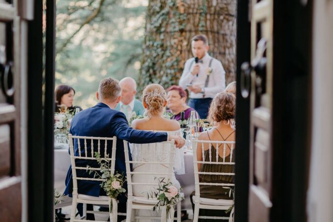 Eine Braut und ein Bräutigam sitzen an einem Tisch im Garten.