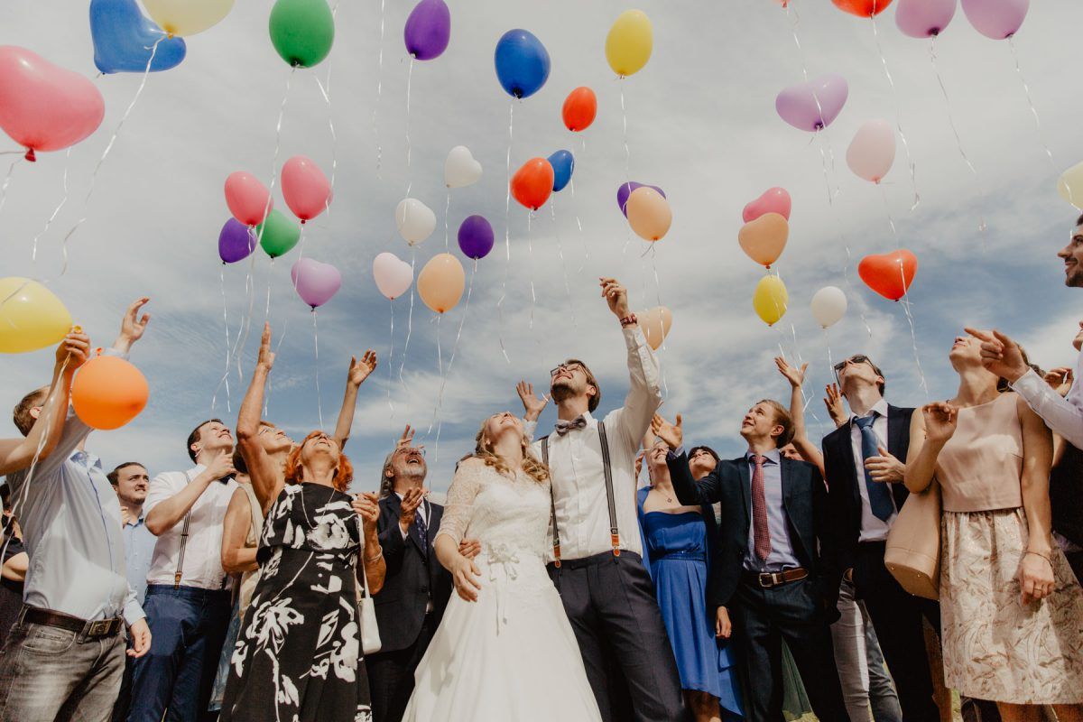 Eine Gruppe Braut und Bräutigam wirft Luftballons in die Luft.