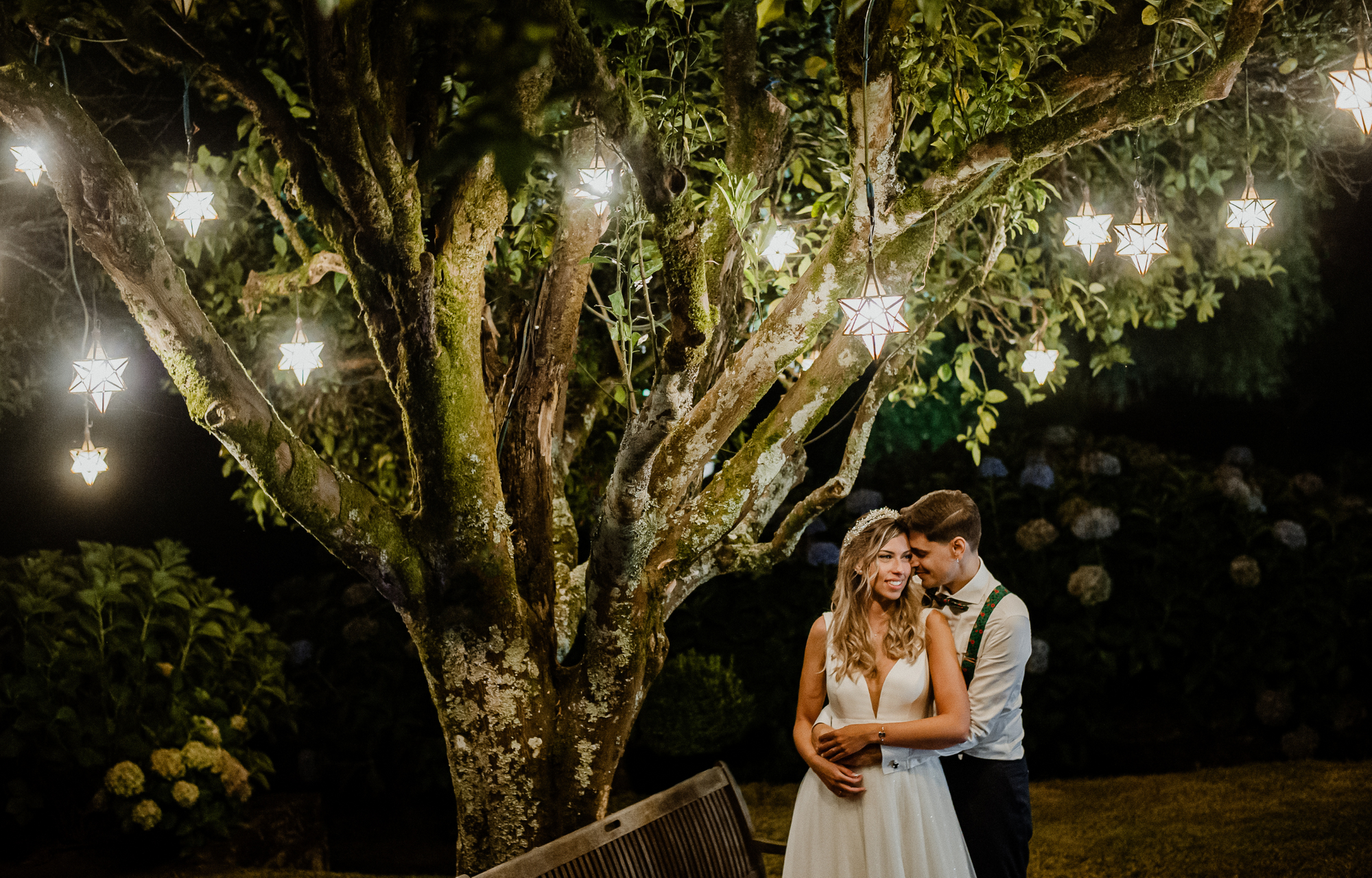 Das Hochzeitspaar steht unter einem Baum, der geschmückt ist mit leuchtenden Sternen.