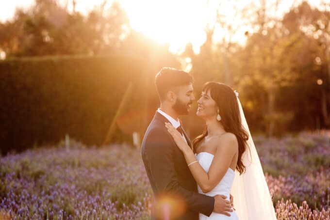 Eine Braut und ein Bräutigam stehen bei Sonnenuntergang in einem Lavendelfeld.