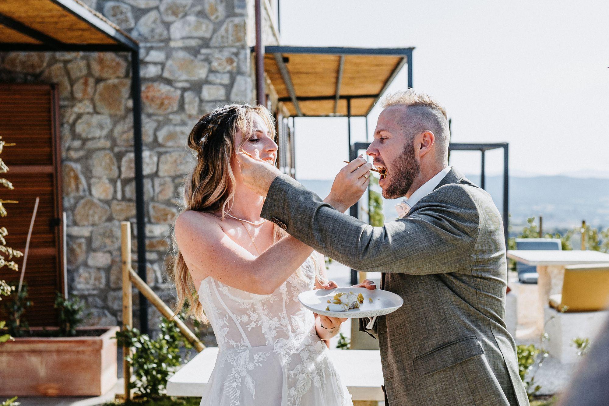 Eine Braut und ein Bräutigam füttern sich gegenseitig mit ihrer Hochzeitstorte.