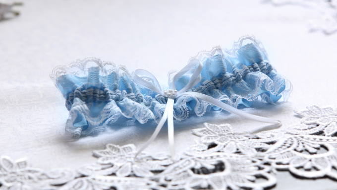 Ein blau-weißes Spitzenstrumpfband auf einem Deckchen.