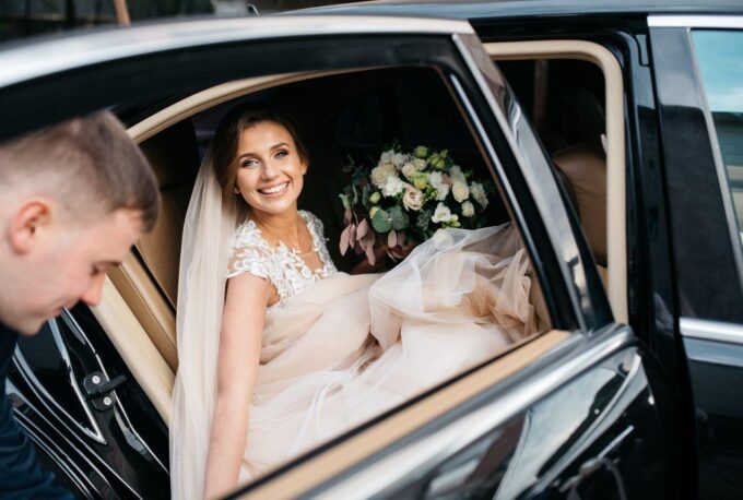 Braut und Bräutigam steigen aus einem Auto.