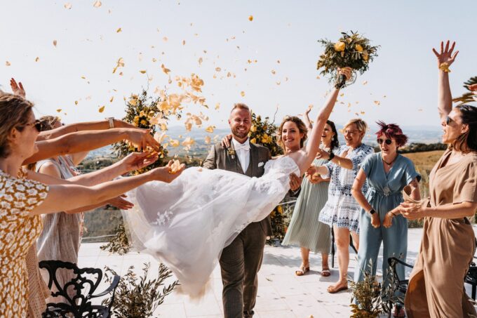 Eine Hochzeitsgesellschaft bewirft Braut und Bräutigam mit Konfetti.
