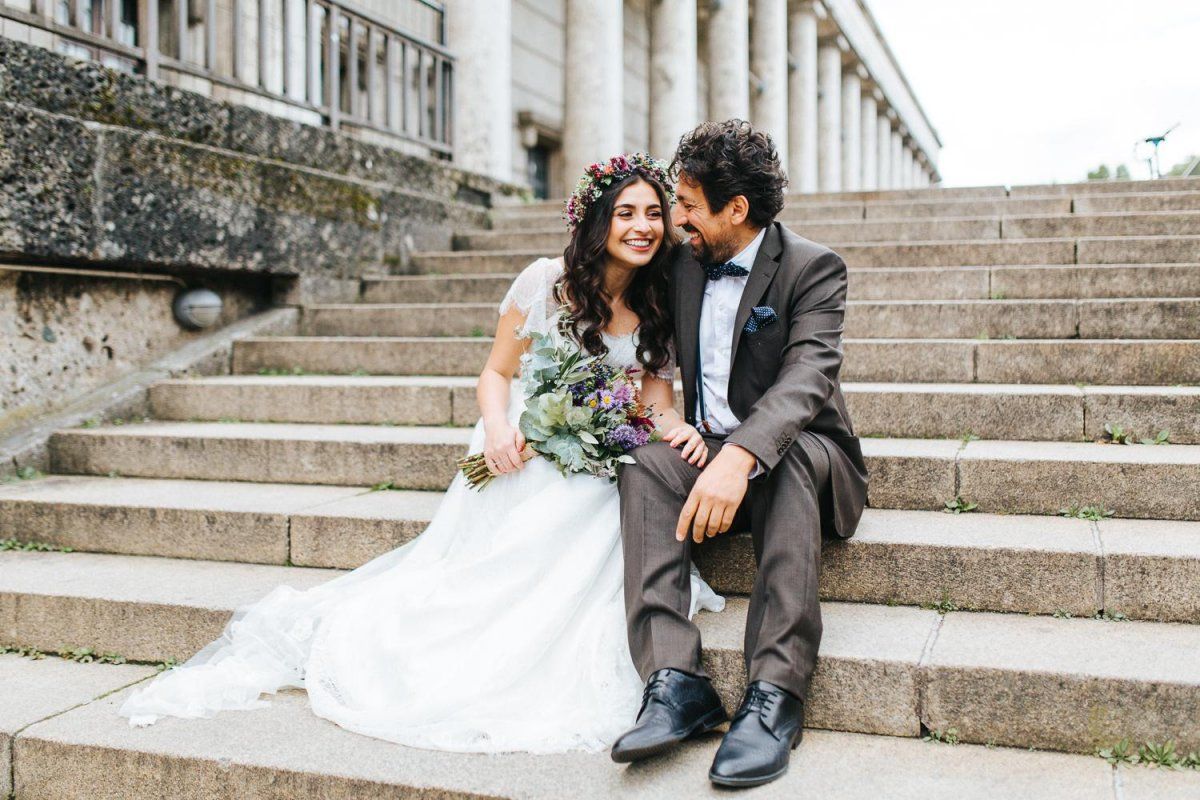 Eine Braut und ein Bräutigam sitzen auf den Stufen eines Gebäudes.