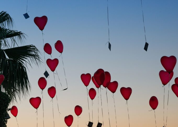 Eine Gruppe roter Herzballons, die in den Himmel fliegen.