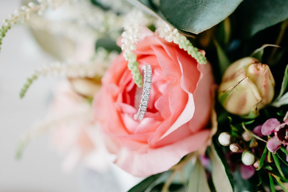 Eine Nahaufnahme einer rosa Rose mit einem Ring darauf.