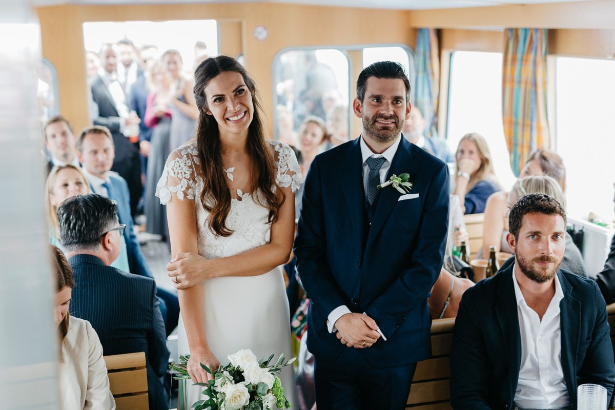 Eine Braut und ein Bräutigam stehen während ihrer Hochzeitszeremonie auf einem Boot.